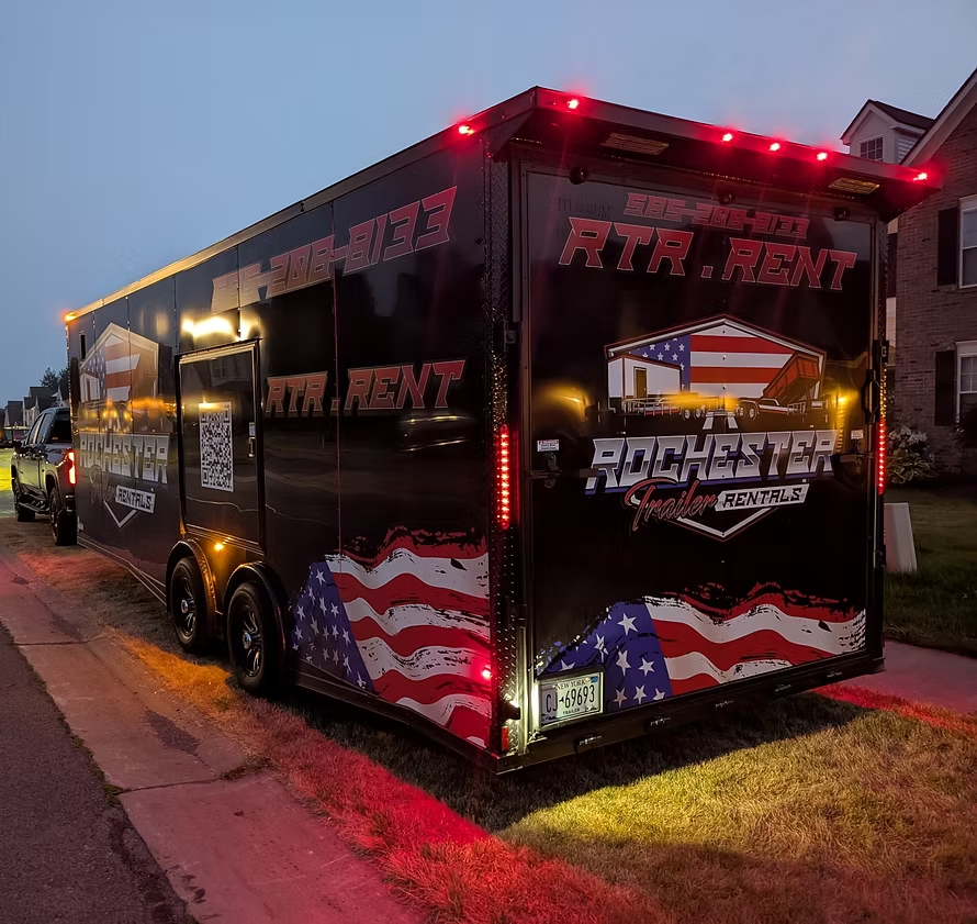 Black enclosed trailer with American flag wrap and red accent lighting at dusk
